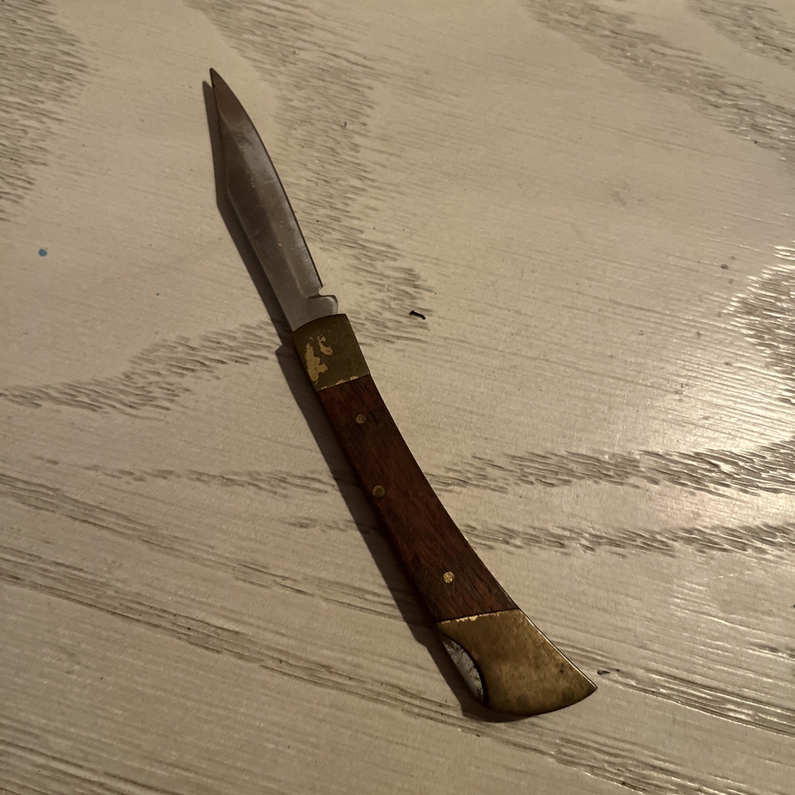 Vintage folding pocket knife with a wooden-like handle and brass bolsters.