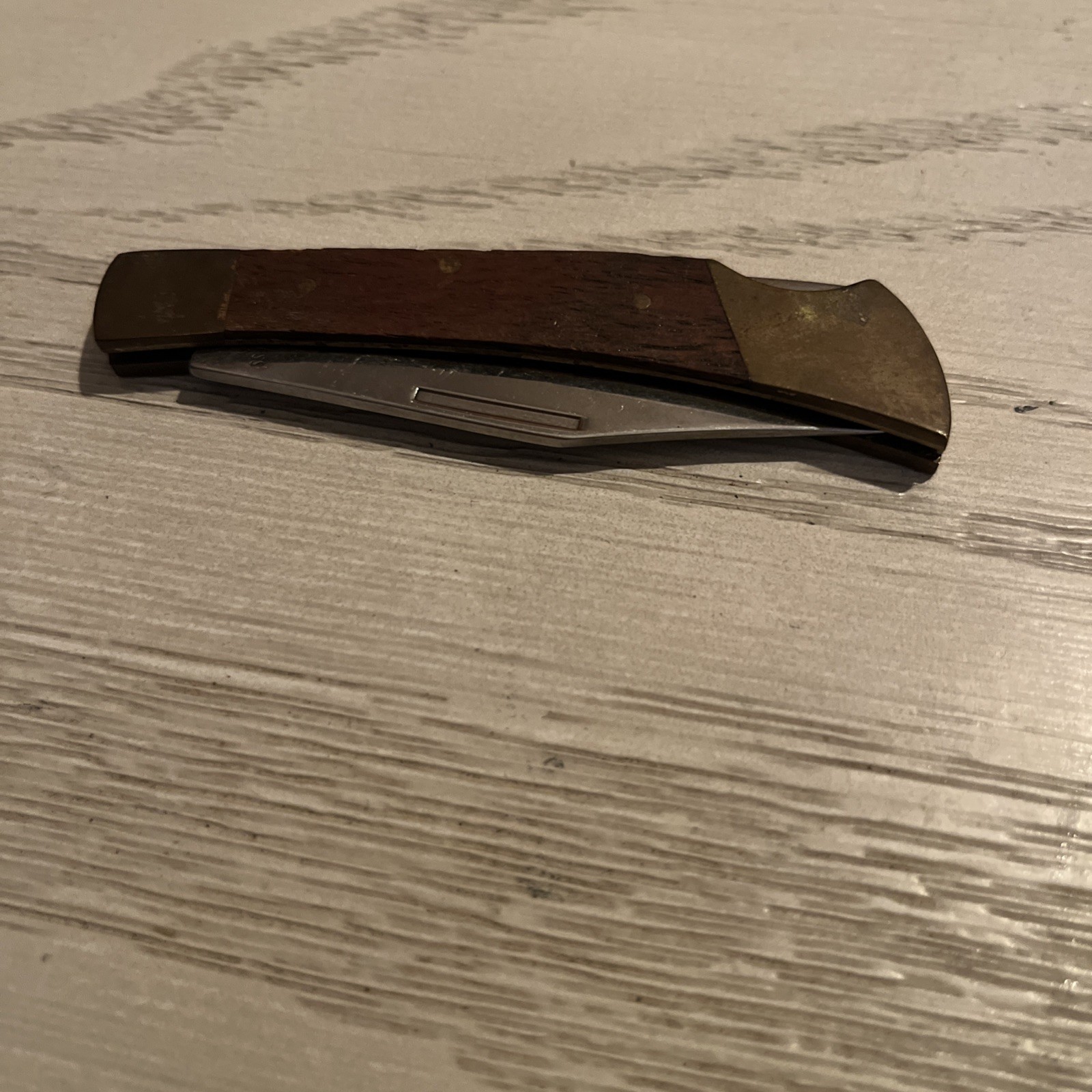 Vintage folding pocket knife with a wooden-like handle and brass bolsters.