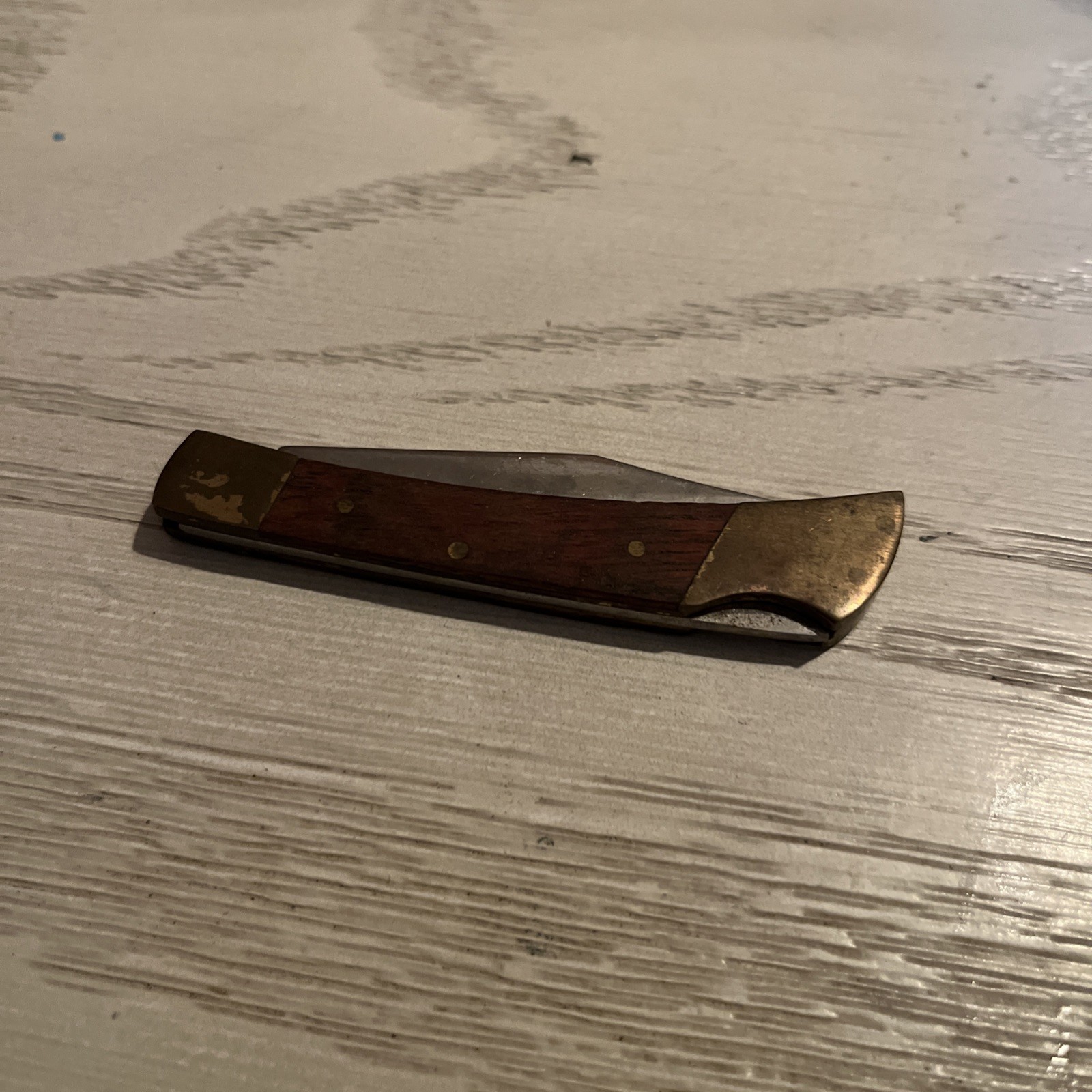 Vintage folding pocket knife with a wooden-like handle and brass bolsters.
